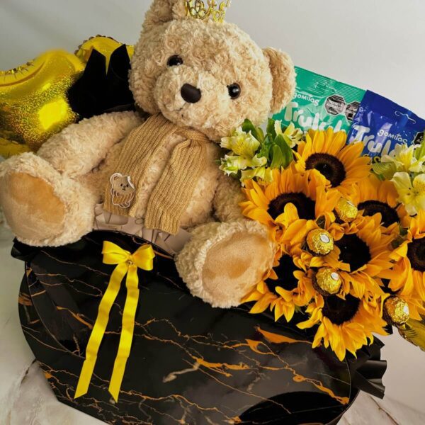 Detalle de peluche y ramo de girasoles en caja negra marmoleada