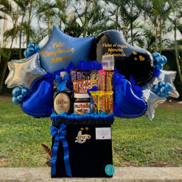 Arreglo de cumpleaños con botella de Old Parr, chocolates y globos personalizados en tonos azules.