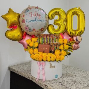 Arreglo de cumpleaños con rosas amarillas, barritas de cereal y perfume réplica en caja redonda blanca