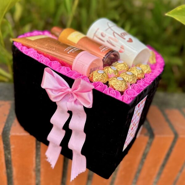 Vista lateral de detalle romántico con base de corazón, loción réplica y chocolates – Regalo para mujer