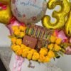 Detalle de globos dorados y rosas amarillas en regalo personalizado para cumpleaños