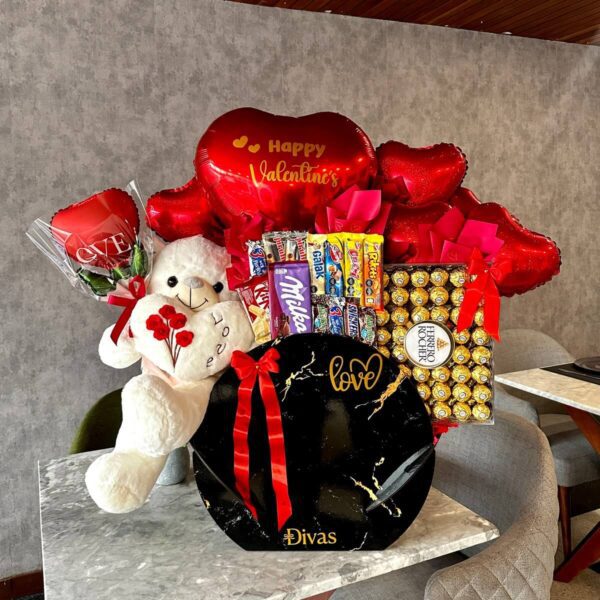Vista completa del regalo con chocolates importados, peluche y globo corazón