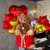 Mujer sosteniendo regalo romántico con peluche grande y chocolates Ferrero