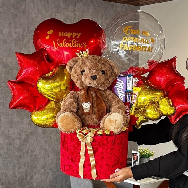 Mujer sosteniendo regalo romántico con peluche grande y chocolates Ferrero