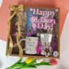 Regalo especial para mamá con chocolates, frutos secos, taza decorativa y cafetera metálica.