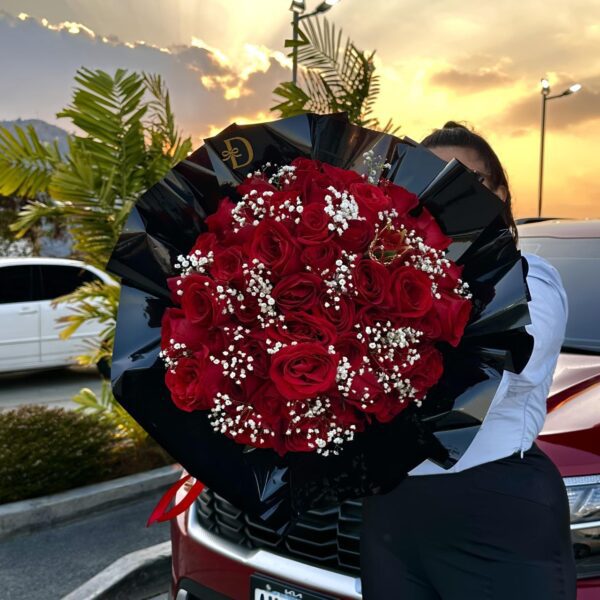 Ramo de rosas rojas con envoltorio negro y detalle de gypsophila